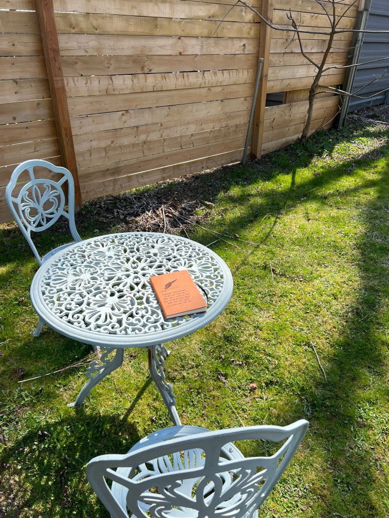 Brown leather diary with inspirational quote, placed outdoors on a table with nature in the background